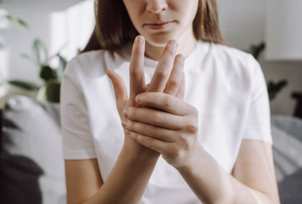 A woman holding her hand to relieve joint pain, arthritis, or carpal tunnel symptoms.