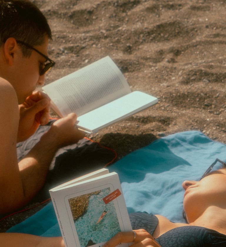 a man and woman reading a book on a blanket