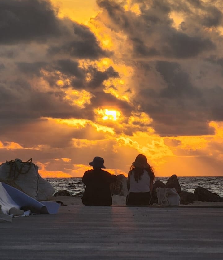 a couple of people sitting on a beach