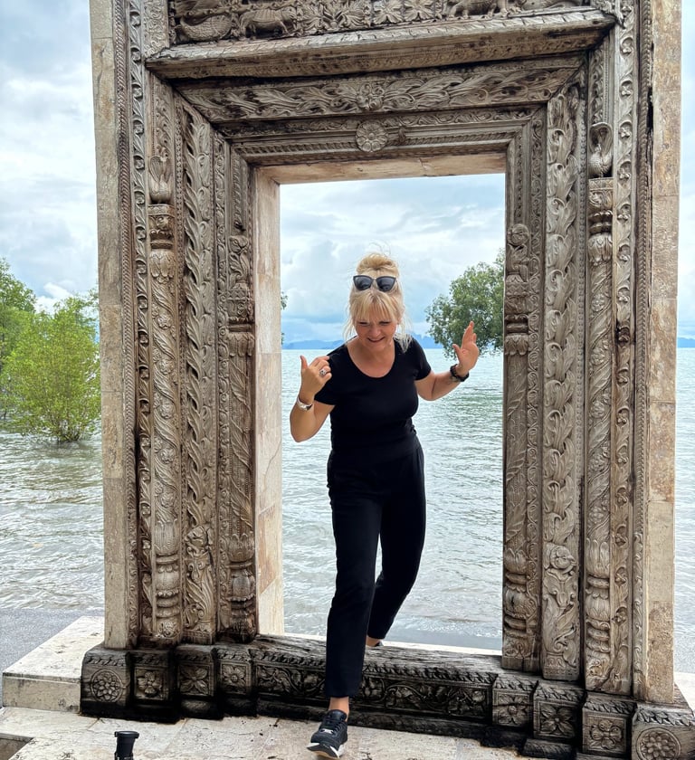 Edyta Vorilhon passant une porte en pierre au bord de l'eau.