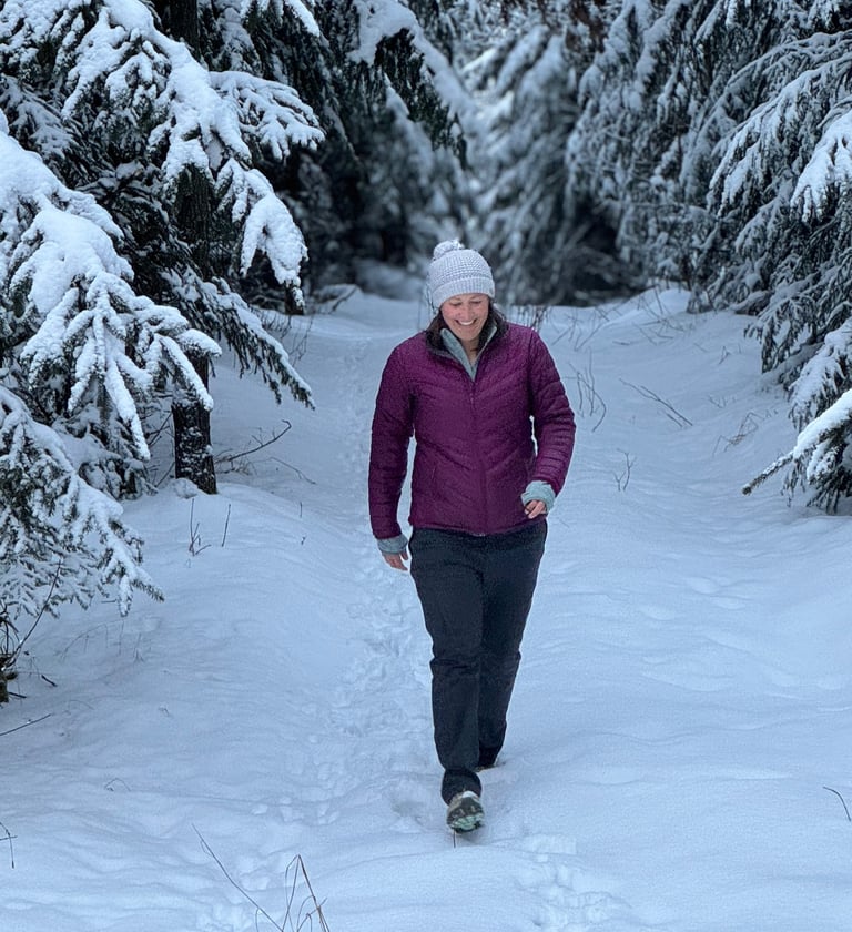 a woman walking through the snow in a forest