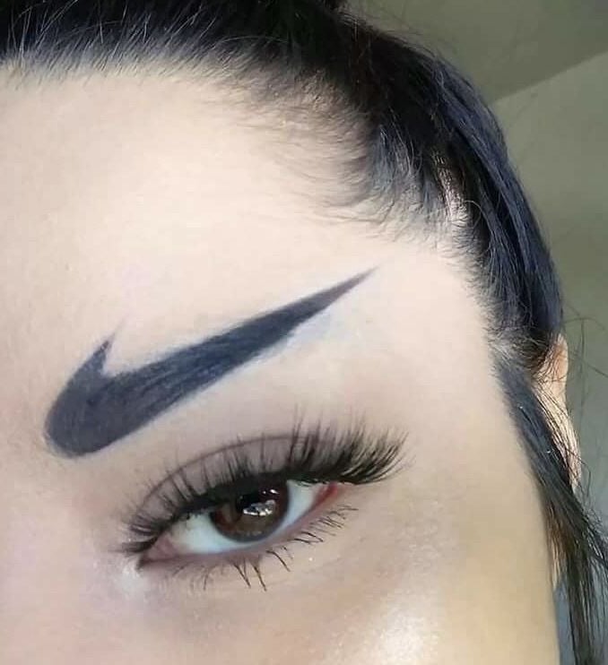 An example of unwanted permanent makeup: a woman with black Nike swoosh logos tattooed as her eyebro