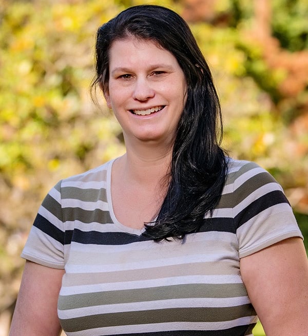 Image of Michelle smiling against background of yellow fall leaves
