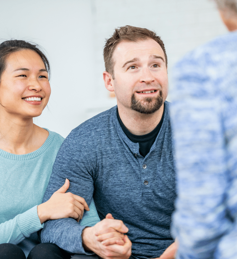 couple smiling and wearing blue shirts attending couples counselling calgary