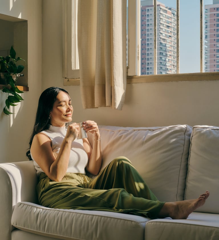 a woman sitting on a couch with a cup of coffee relaxing