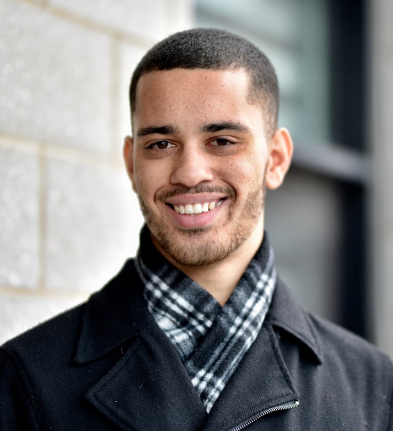 man in a black pea coat and a plaid scarf