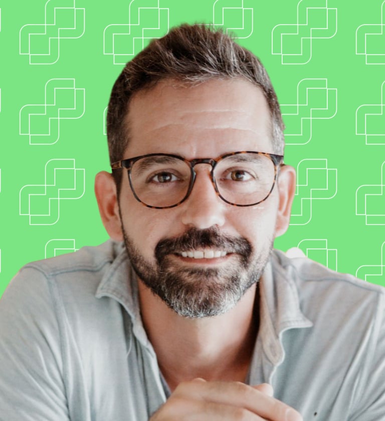 A professional headshot of Michael Franco with a green background. He is in a blue shirt and wearing glasses.