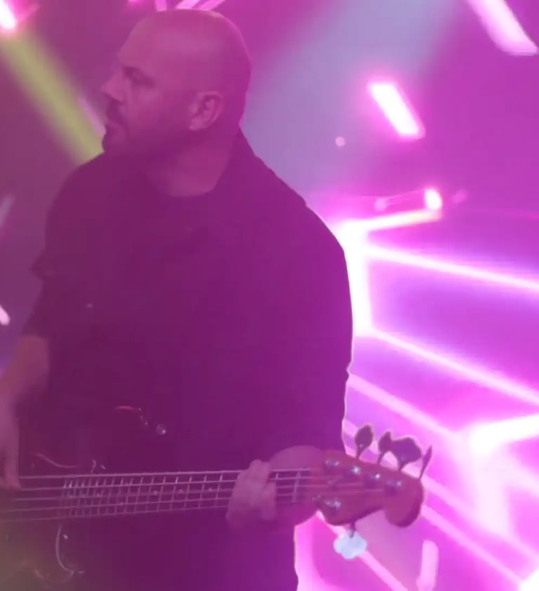 a man with a guitar and a guitar in front of a purple light