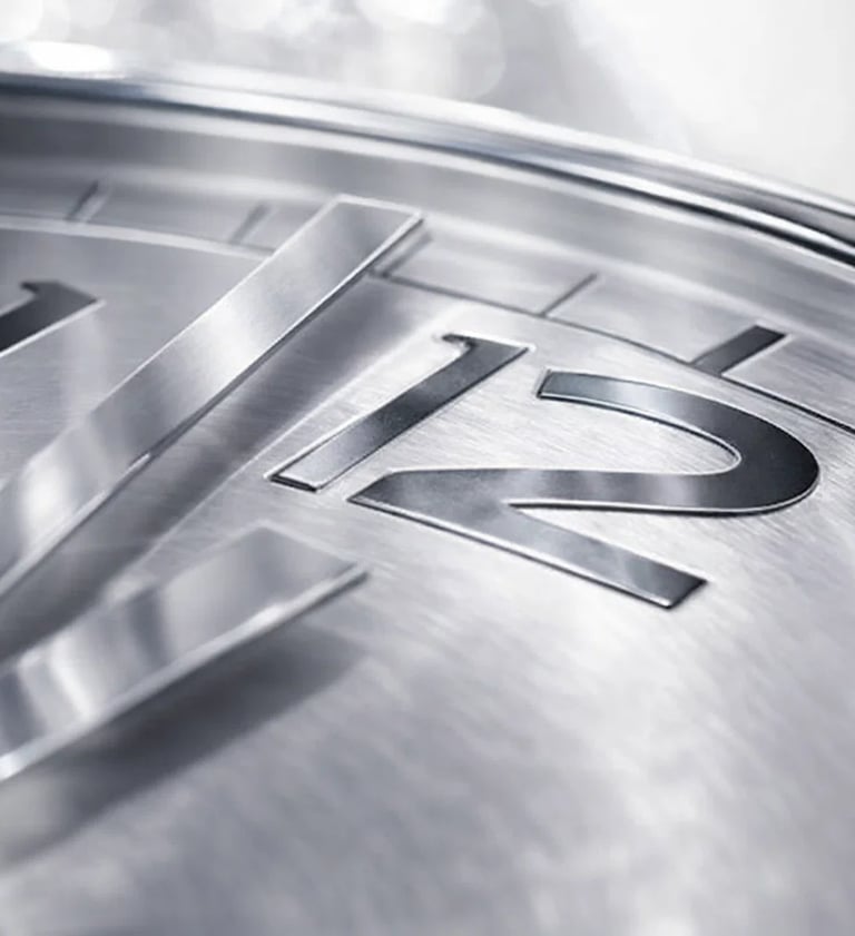 Close-up of a silver luxury watch face with brushed metal texture and 12 o'clock numeral.