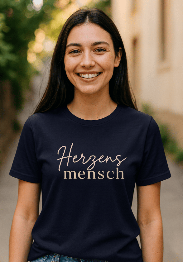 Lächelnde Frau trägt dunkelblaues Heartful Apparel T-Shirt mit Schriftzug ‚Herzensmensch‘ in Beige