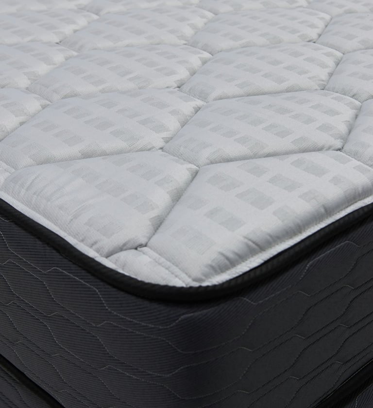 Close‑up of a mattress corner showing quilted top and stitched side panel.