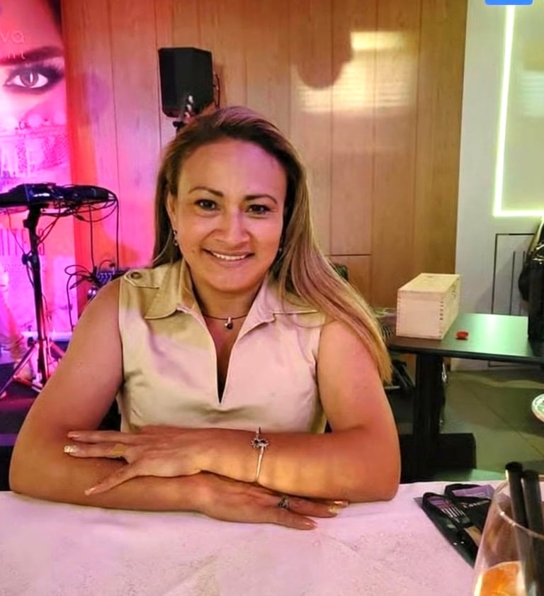 Smiling woman with blonde hair sitting at a dinner table in a restaurant with warm lighting.
