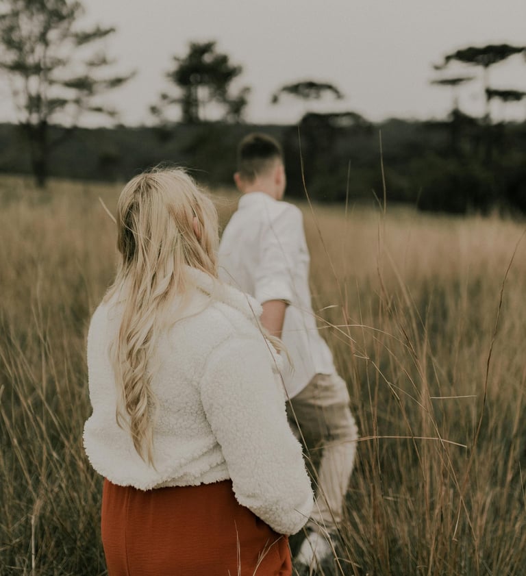 a man and woman standing in tall grass