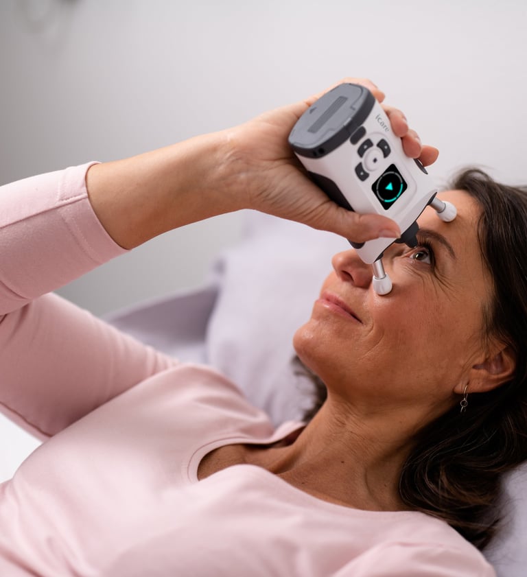 Woman lying down measuring her eye pressure IOP with an iCare HOME2 tonometer.