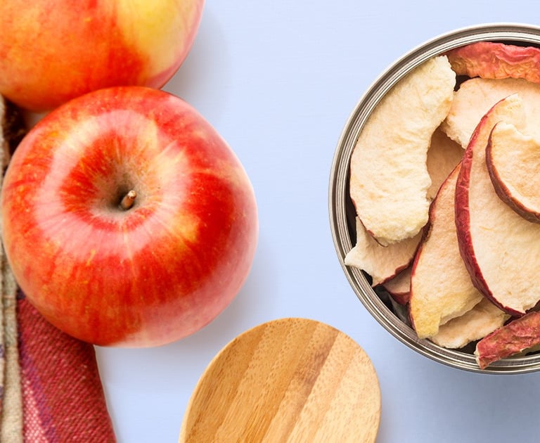 fresh red apple near open can of freeze dried apples