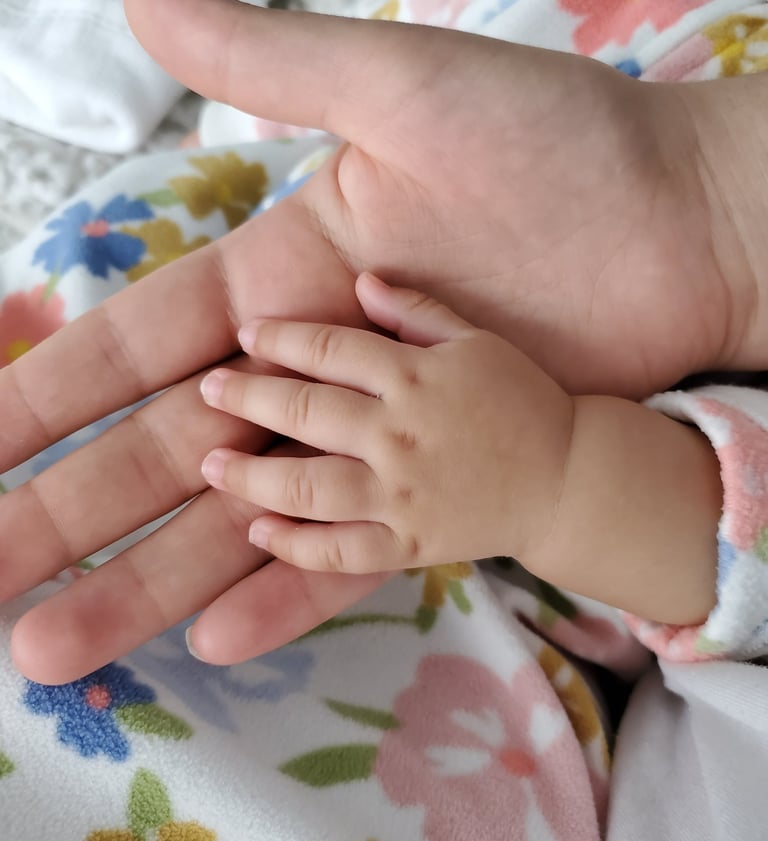 A mom's hands holding a baby's hand