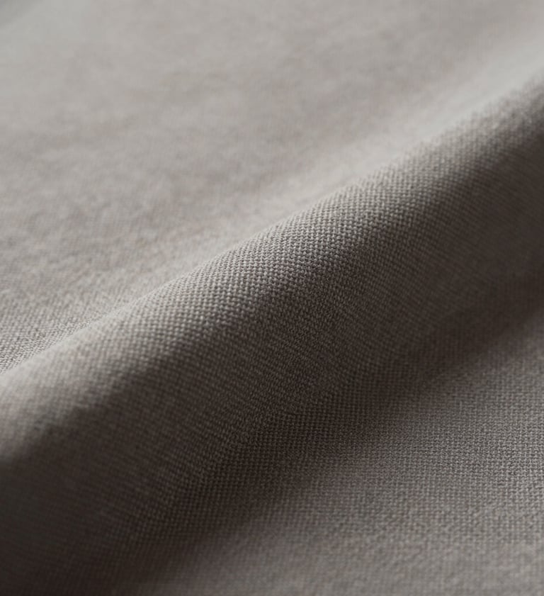 Close-up artistic photograph of textured fabric in shades of #6B625E and #AEAEA7. The lighting is soft and cinematic, highlighting the intricate weave. Minimalist composition with a dark #26211F shadow in the corner. Sophisticated and professional style.