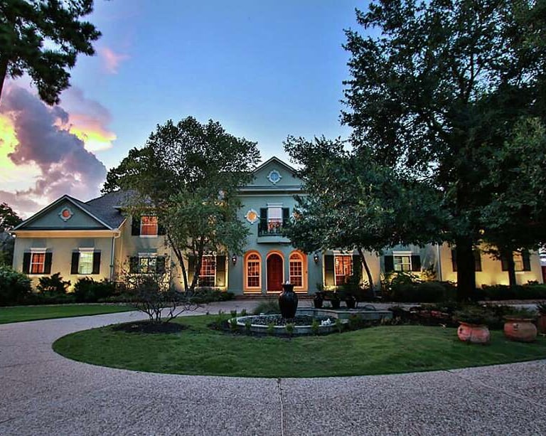 a large house with a fountain in the middle of the yard