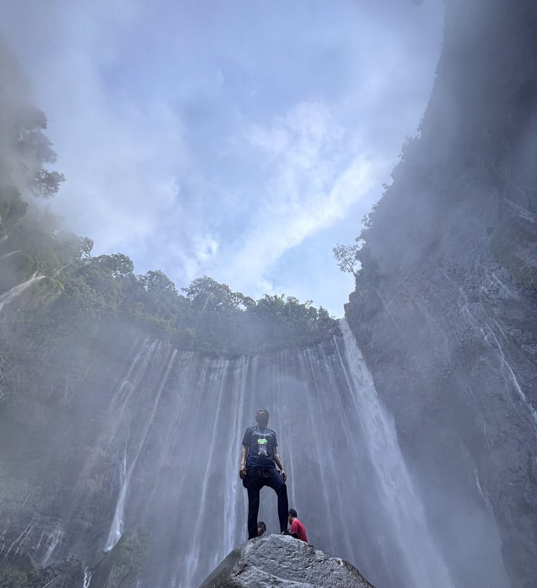 a man standing on a rock in front of a waterfall