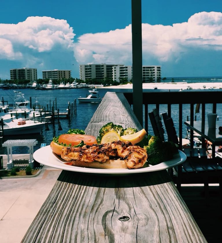 a plate of food on a table with a view of a boat in the background