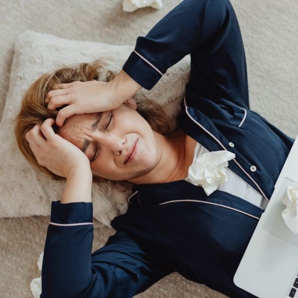 a woman in pajamas crying and is laying on a pillow
