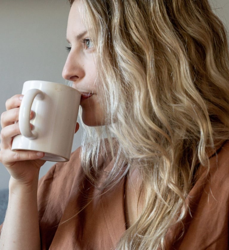a woman with blonde hair and a brown shirt is drinking a cup of coffee