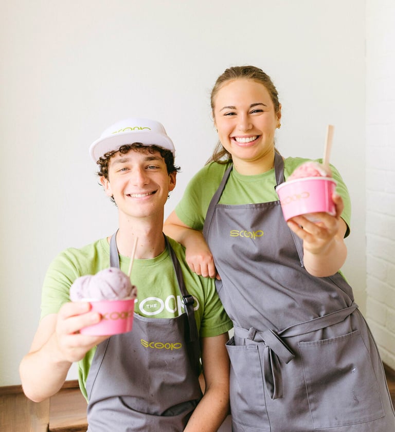 The Lafayette Scoop team male and female holding pink hard serve ice cream cups in Scoop logo