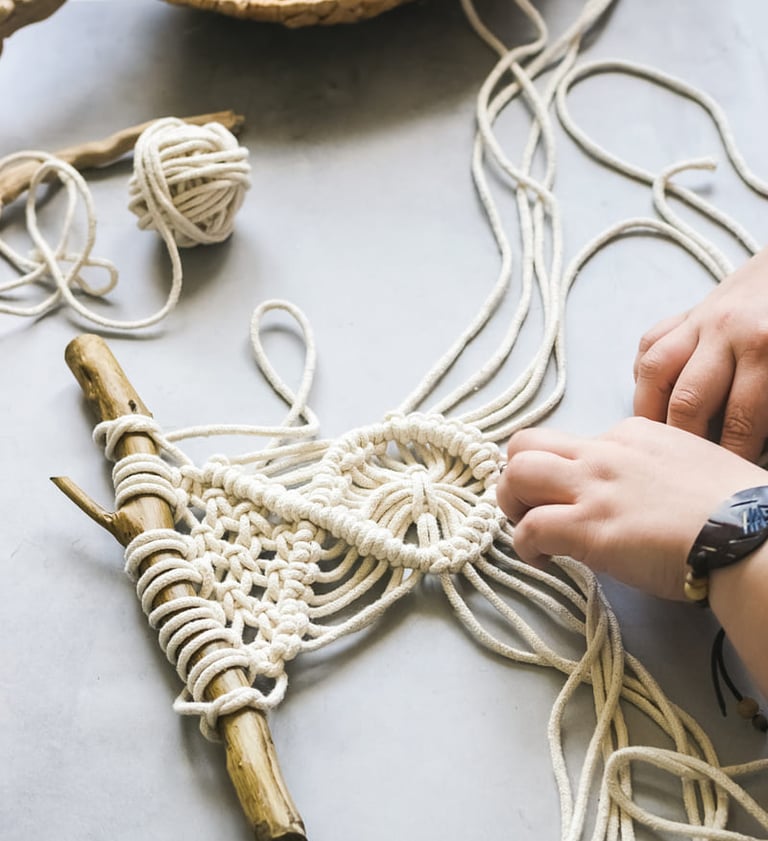 proyecto pequeño de macrame en blanco sobre un tronco de madera