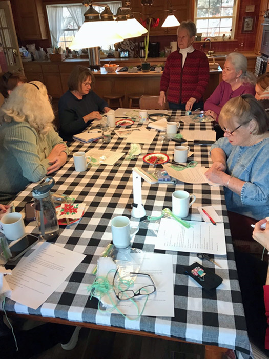 a group of ladies sitting around a table sewing