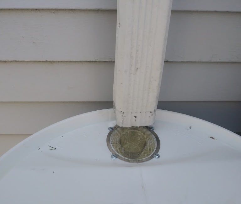 a photo of a rain barrel installed under a cut downspout for collecting rainwater