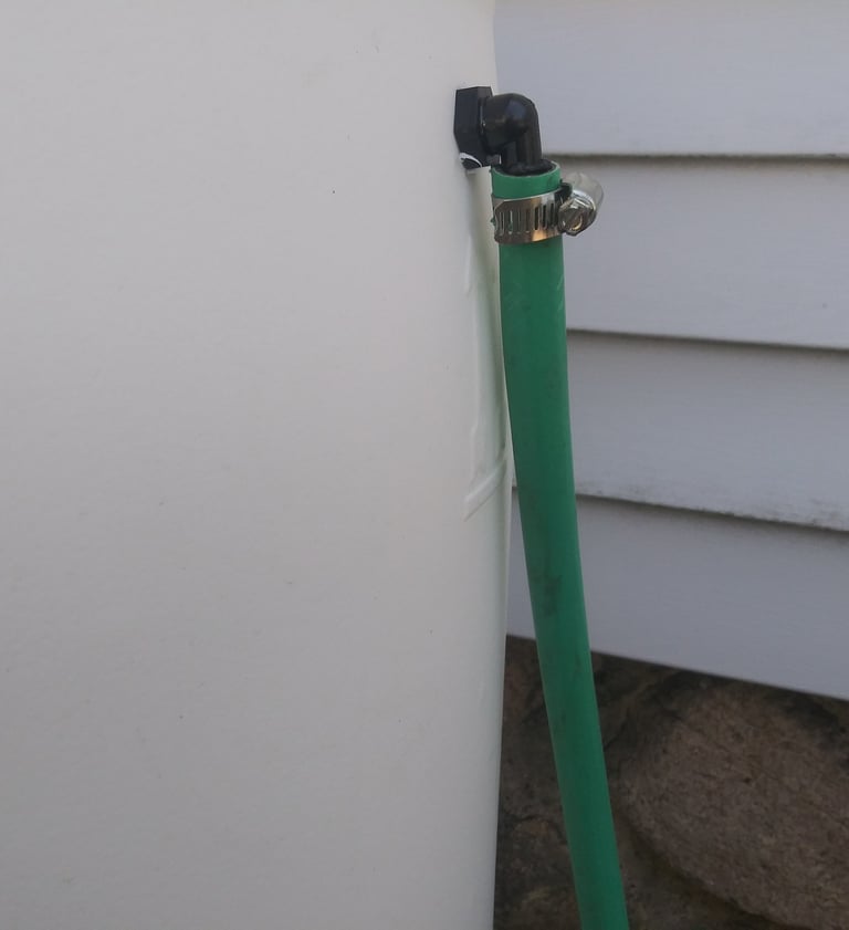 a hose clamped onto a rain barrel overflow
