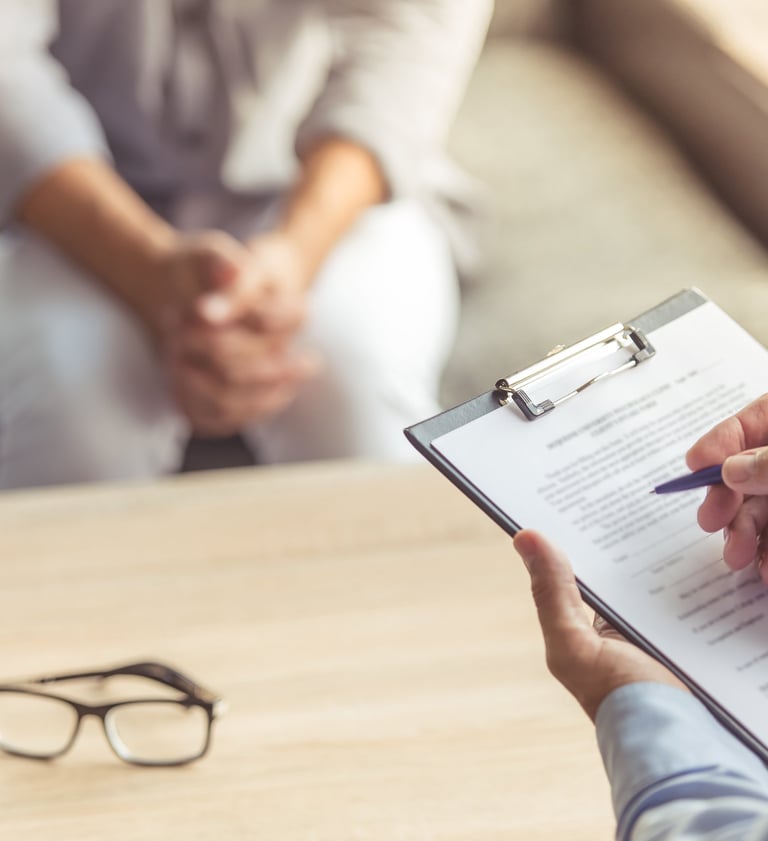 Zwei Personen in einer Psychotherapiesitzun. Der Psychotherapeut macht sich Notizen.