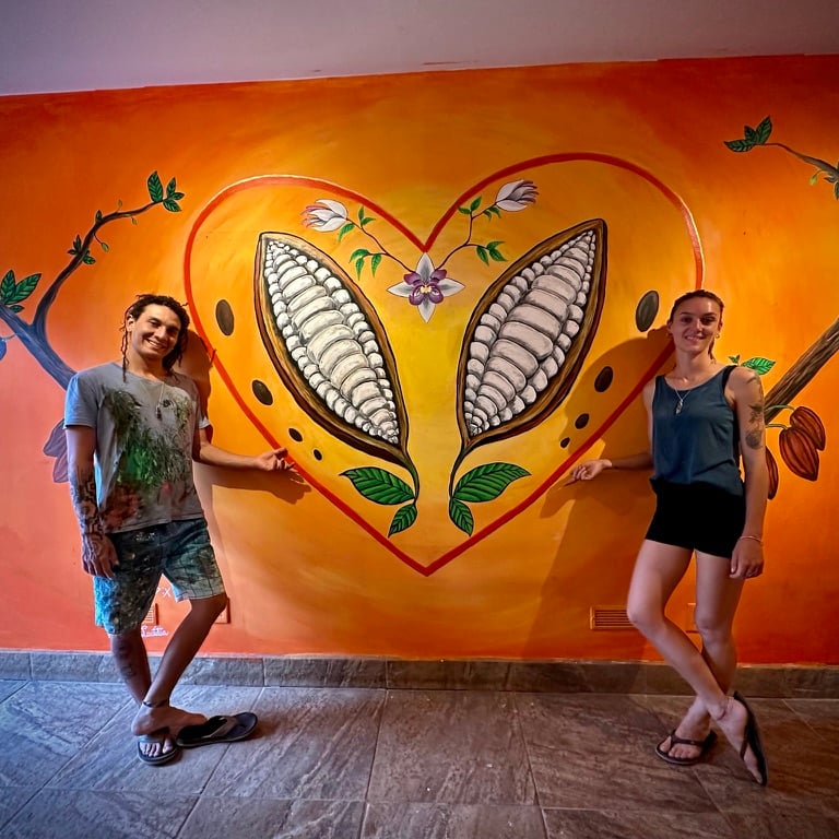 Man and woman standing near cacao mural at Reina's Chocolate in Costa Rica