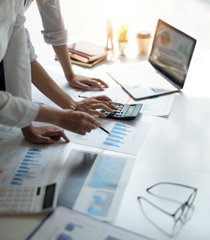 Tim profesional sedang menganalisis data bisnis dengan grafik dan laptop di meja kerja.