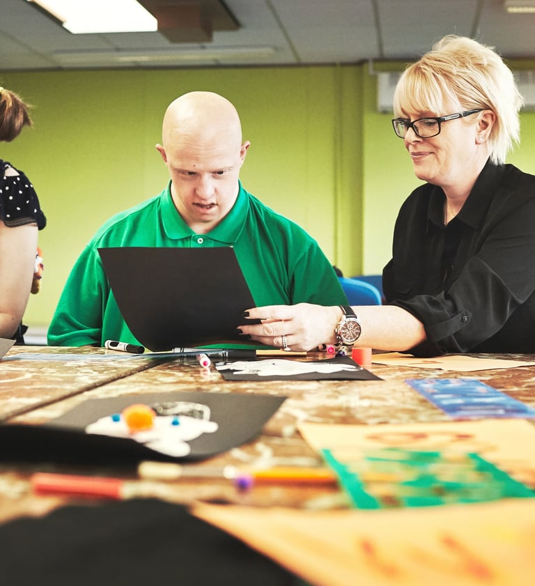 a man and woman sitting at a table with a laptop