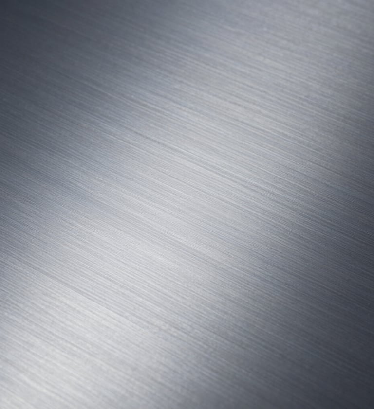 Close-up photography of a brushed metal surface showing fine, elegant texture. Professional studio lighting with cold, silvery tones. Minimalist and refined Northern European style.