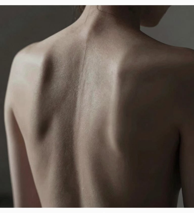A chiaroscuro photograph focusing on the artistic expression of a human back, soft light tracing the spine, deep shadows in #1F1E1C, skin tones in #F5F2EF, refined and intimate composition.