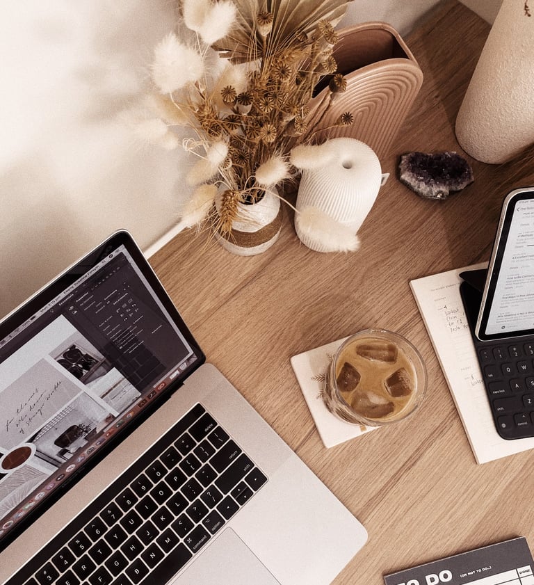 Aesthetic home office desk with laptop, iced coffee, dried flowers, and productivity planner.