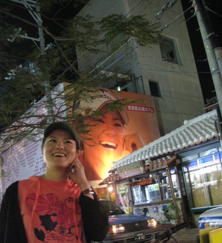 a japanese woman in a red shirt talking on a cell phone