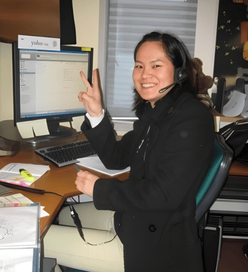 a japanese woman sitting at a desk with a computer and a laptop