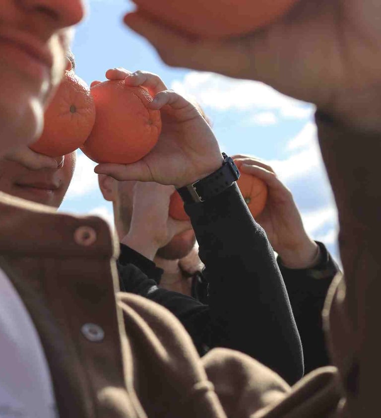 zmones ziuri i toli su apelsinais prie veido