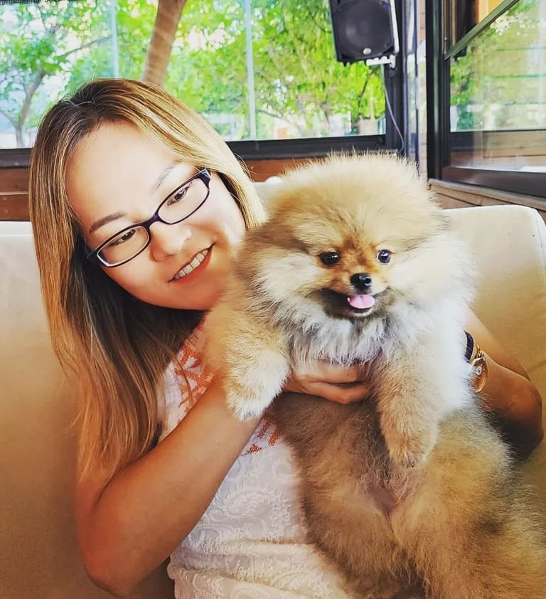 a japanese woman in glasses and a white shirt is holding a dog