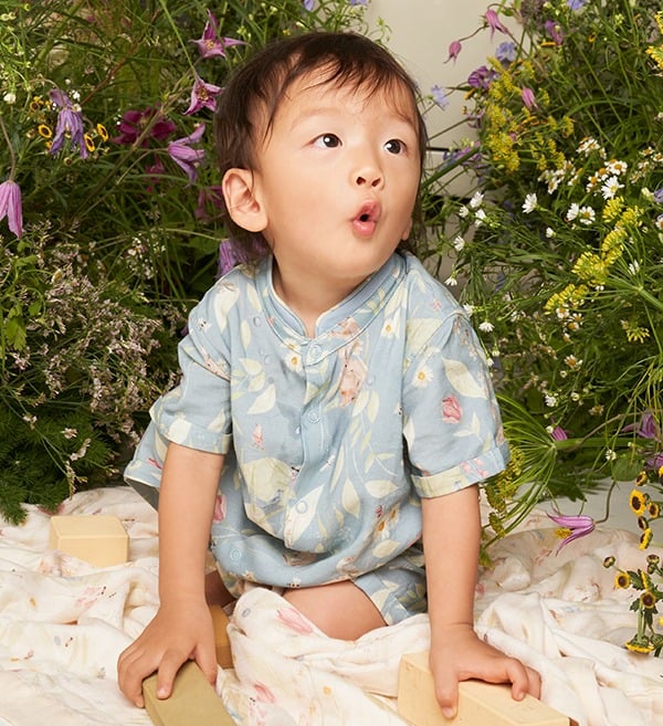 Bebê asiático veste macacão com estampa de arte original criada a mão da vida de um jardim