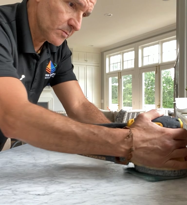 Professional contractor using a power sander for marble countertop restoration and honing