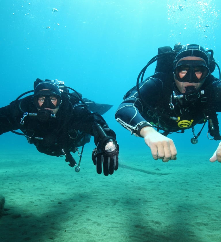 two scuba divers in full bodysuits and diving gear