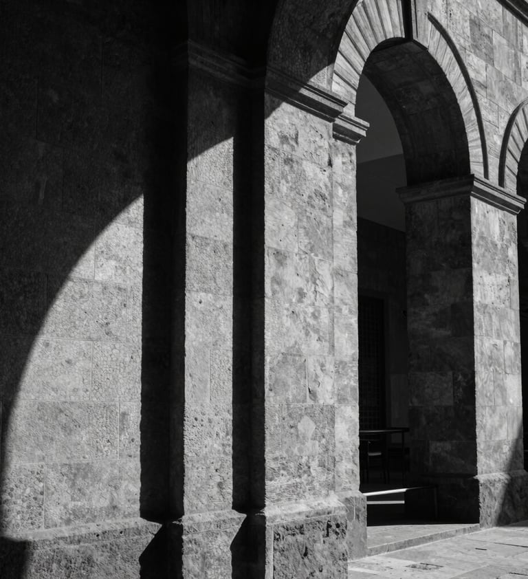 Black and white photography, architectural detail of the Laboratorio Arte Alameda in Mexico City, focusing on the interplay of light and shadow on stone walls, cinematic and contemplative style.