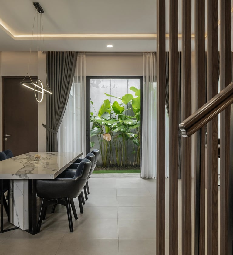 Interior ruang makan yang elegan dengan meja makan dari marmer, kursi beludru biru tua, dan lampu ga