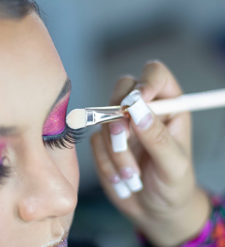 Maquilladora profesional que aplica sombras de ojos con brillo rosa vibrante con un pincel