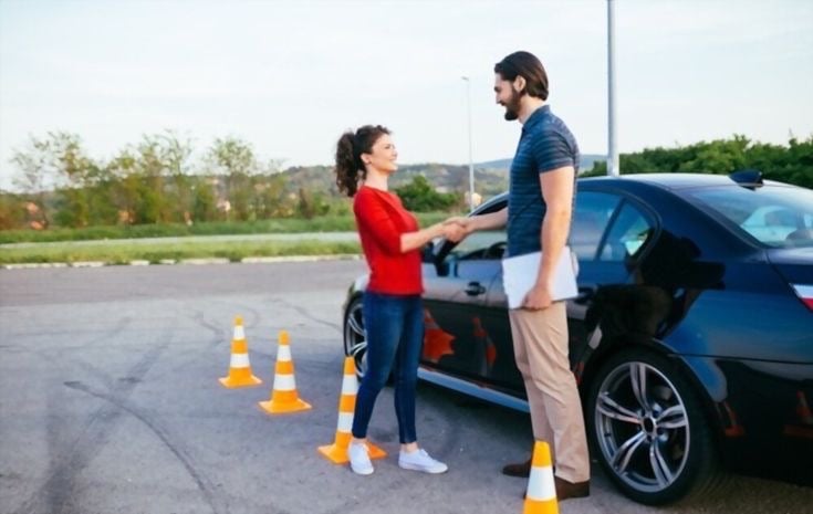 Instruktorius pasveikina mokinę B kategorijos kursuose