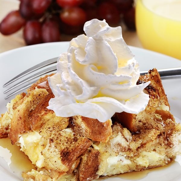 a piece of bread pudding with whipped cream on top of it